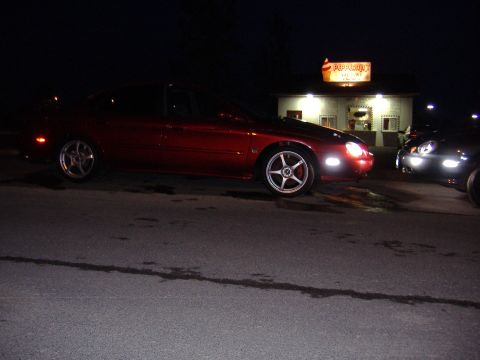 1998 Ford Taurus - A red 1998 Ford Taurus is parked at night in front of a building.