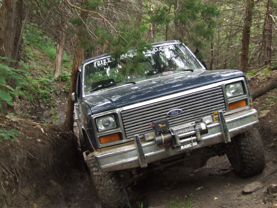 1986 Ford Bronco navigating a wooded trail, front winch visible