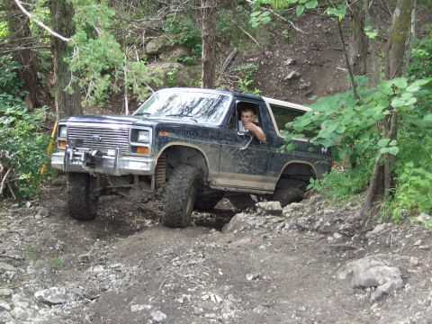1986 Ford Bronco - This modified Ford Bronco is shown tackling a challenging off-road trail with steep grades and loose rocks.