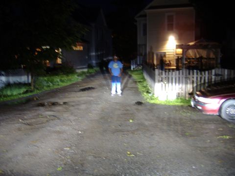 1998 Ford Taurus - A person stands in a dimly lit driveway at night, with a car parked to the right.