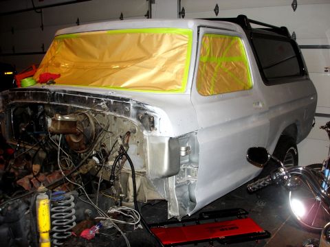 1979 Ford Bronco - This Ford Bronco is undergoing repairs in a garage, with its front end stripped down and windows covered for protection.