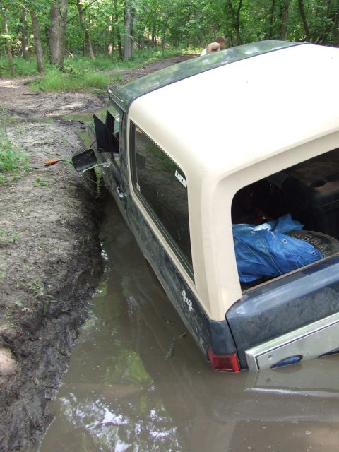 1986 Ford Bronco - This 1986 Ford Bronco is stuck deep in a muddy trail, with its tires submerged.