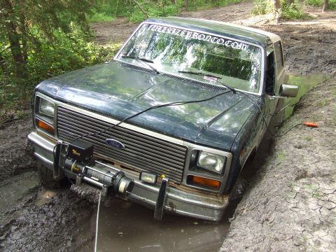 1986 Ford Bronco - This Ford Bronco is stuck in a muddy trail, with its front end deep in the mire and a winch attached.