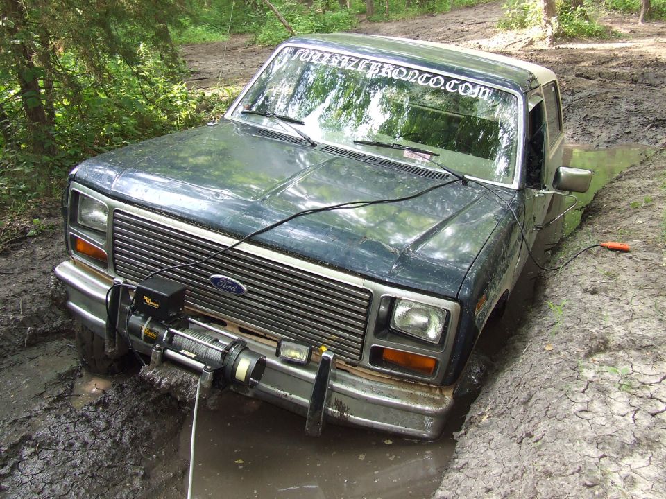 Ford Bronco stuck in a muddy ditch, winch mounted on front bumper