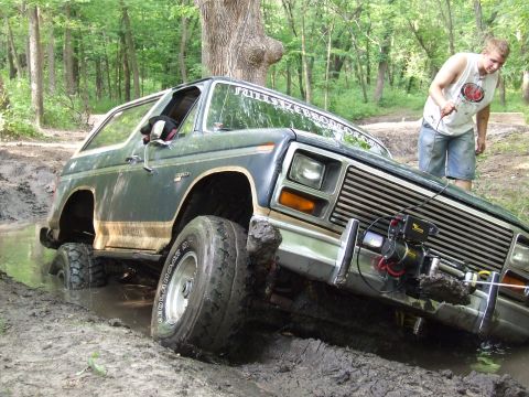 1986 Ford Bronco - Ford Bronco stuck in mud with a winch attached to the front bumper.
