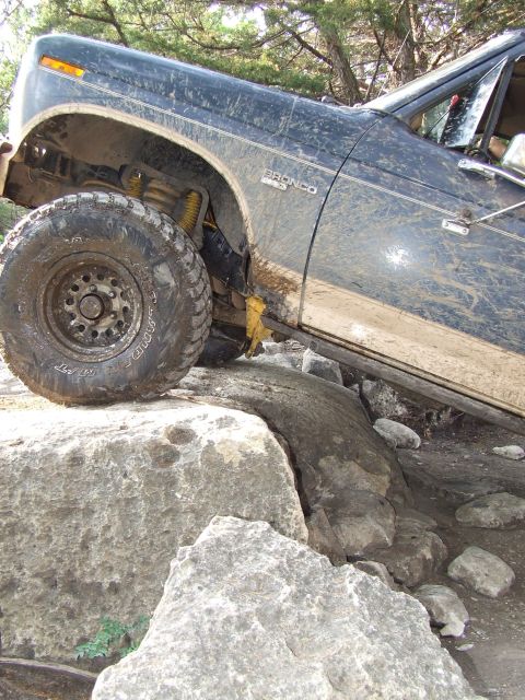 1986 Ford Bronco - This 1986 Ford Bronco is shown off-roading over large rocks, demonstrating its capability on challenging terrain.