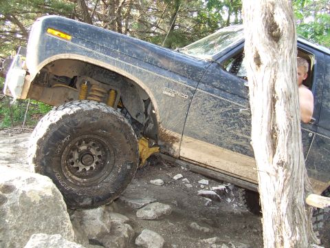 1986 Ford Bronco - This 1986 Ford Bronco is navigating a rocky off-road course, with mud splattered across its body.