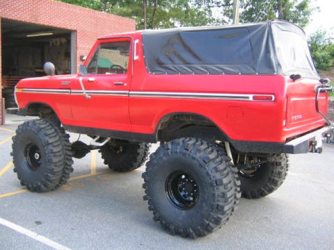 1979 Ford Bronco - This lifted red Ford Bronco, likely a 1978 model, is modified with a black soft top and oversized tires.