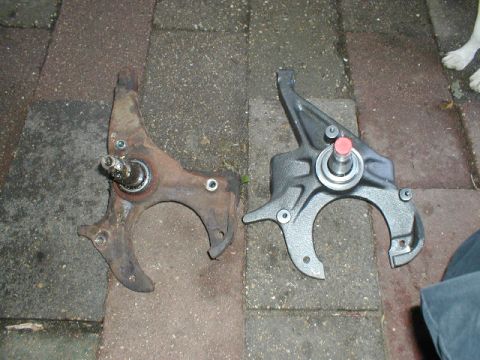 1998 Ford Taurus - A comparison of a used and new car suspension component is shown on a brick surface.