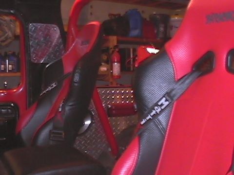 1979 Ford Bronco - Interior view of a vehicle equipped with racing seats, harnesses, and a roll cage.