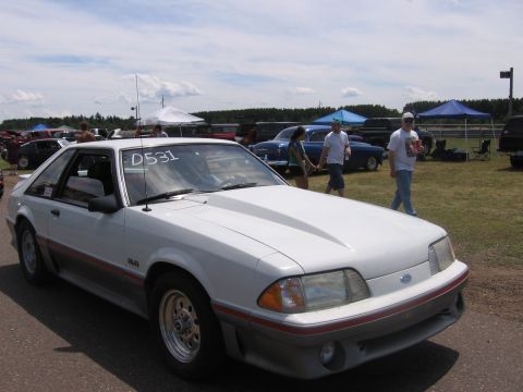 1989 Ford Mustang - White 1989 Ford Mustang parked at an outdoor event with other cars in the background.