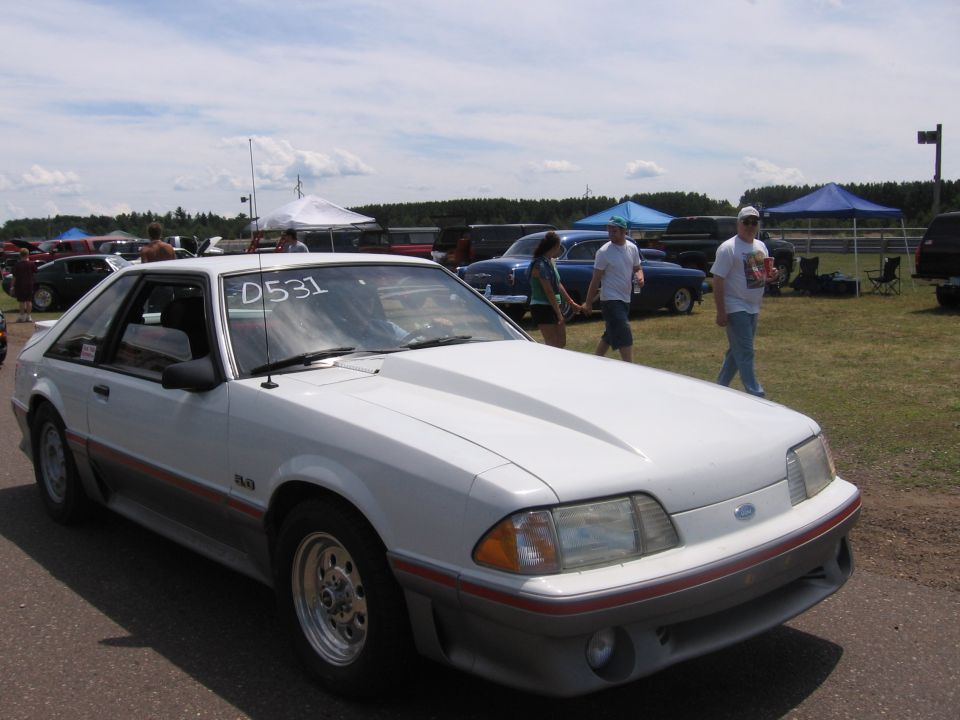 White 1989 Ford Mustang with a cowl induction hood and red/grey side trim