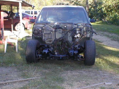 1998 Ford Taurus - Car chassis with engine bay removed, revealing suspension and wiring components.