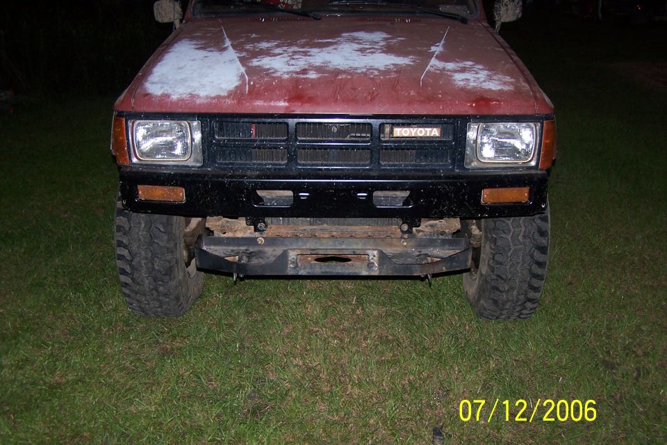 Red 1984 Toyota 4Runner front with a black bumper and winch, showing faded paint on the hood