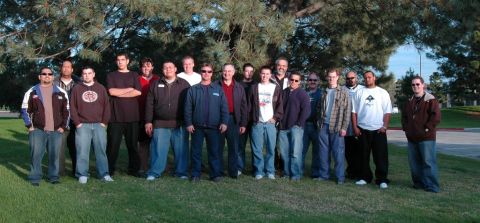 1991 Ford Taurus - A group of men pose for a photo outdoors, with trees and a grassy area in the background.
