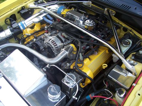 2002 Ford Mustang - Close-up view of a modified engine bay, yellow painted valve covers and various chrome components.