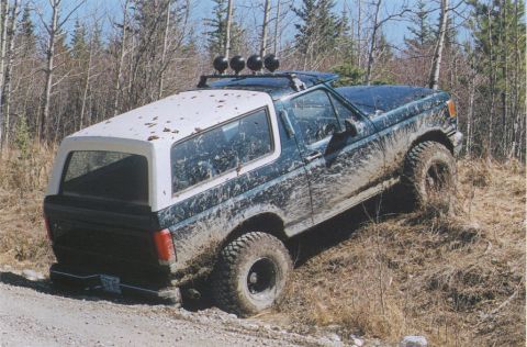 1988 Ford Bronco - Ford Bronco with removable top is stuck in the mud on an off-road trail.