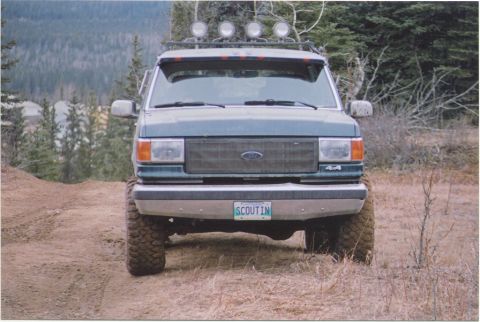 1988 Ford Bronco - A green Ford Bronco is seen from the front on a dirt path with trees in the background.
