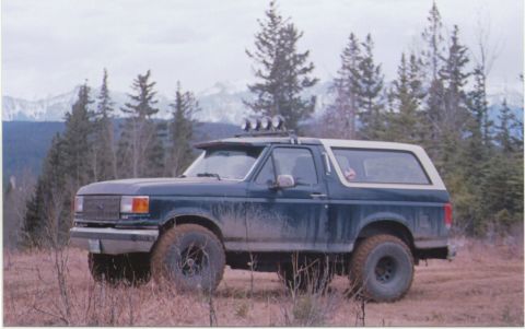 1988 Ford Bronco - Ford Bronco parked on a dirt track with trees and mountains in the distance.