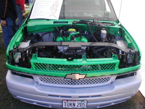 1998 Ford Taurus - The front of a green pickup truck is shown with its hood open, revealing the engine bay and various components.