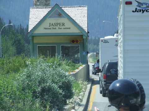 1988 Ford Bronco - Traffic queues at the Jasper National Park entrance station, with mountains and forests in the background.