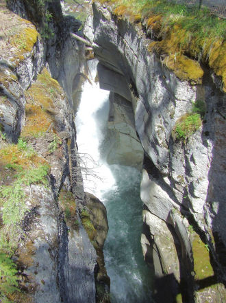 1988 Ford Bronco - A powerful waterfall flows through a deep, rocky canyon, surrounded by lush green moss.