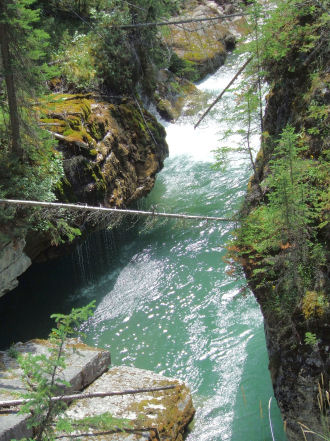 1988 Ford Bronco - A scenic view of a river flowing through a canyon, surrounded by lush green trees and rocky cliffs.