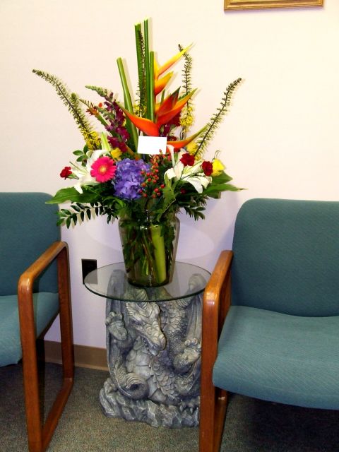 1977 Ford F-150 - A vibrant floral arrangement sits on a unique table with a dragon sculpture base, flanked by two chairs.