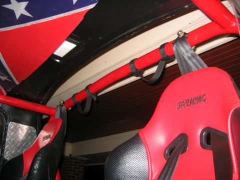 1979 Ford Bronco - Interior view of an open-top truck showing red racing bucket seats branded "3R Racing," a red padded roll cage bar with black nylon grab lo…