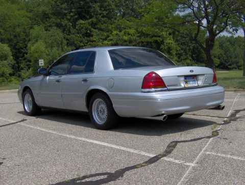 2002 Ford Crown Victoria - Rear 3/4 view of a silver 2002 Ford Crown Victoria, showing its distinctive taillights and license plate.