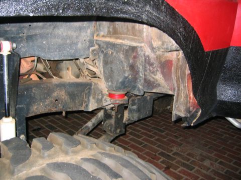 1979 Ford Bronco - Detail shot of vehicle suspension components, including a red urethane bushing and white shock absorber.