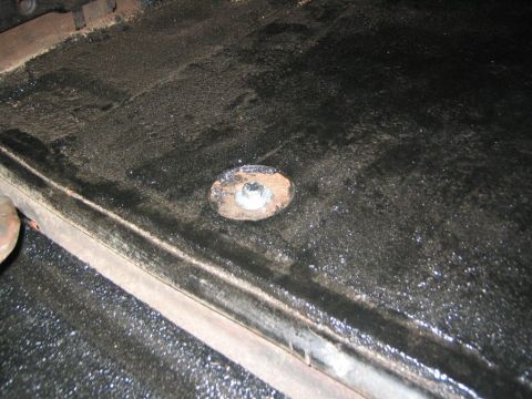1979 Ford Bronco - A close-up view shows a bolt and washer on a dark, wet surface, possibly part of a vehicle's undercarriage or floor.