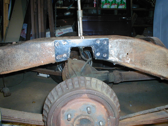 Rusted vehicle frame with a welded metal bracket, rear axle, and drum brake