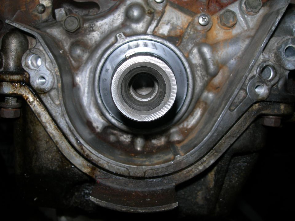 Close-up of an engine's crankshaft seal area, showing wear and oil residue