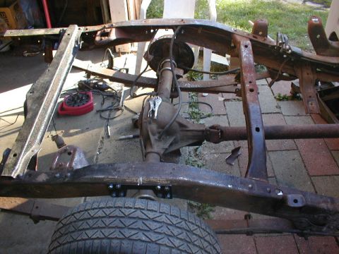 1998 Ford Taurus - Close-up of a heavily rusted vehicle frame, showing the rear axle and a tire.