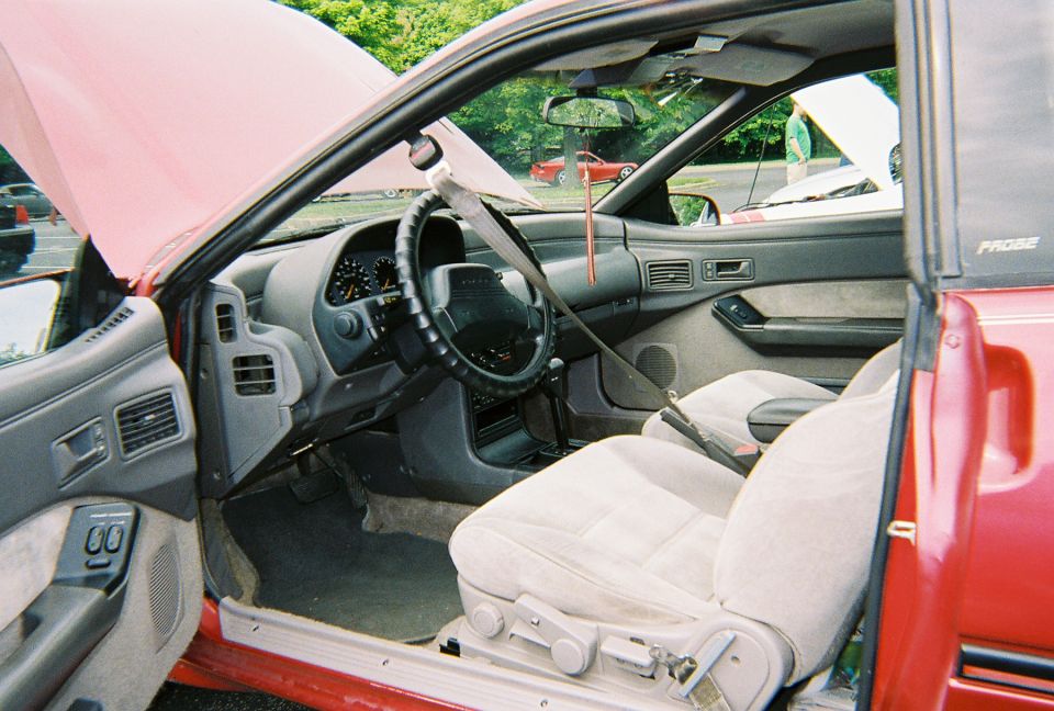 Gray interior of red Ford Probe with manual shifter and steering wheel club lock