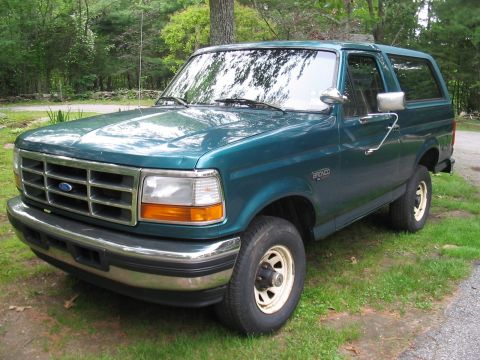 1996 Ford Bronco - A teal 1996 Ford Bronco is parked on a grassy area next to a gravel path.