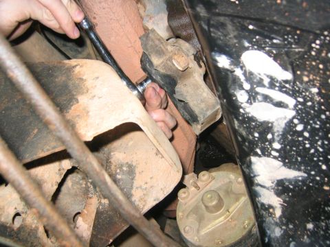 1979 Ford Bronco - Working on a vehicle's engine mount with a wrench, starter motor visible.
