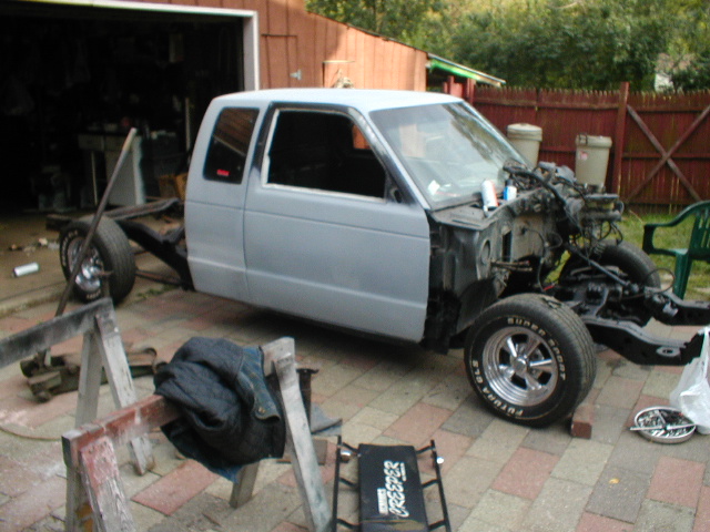 Light gray pickup truck chassis with cab, front wheel visible