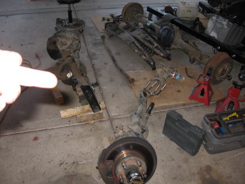 1990 Ford Bronco - Various axle assemblies and suspension components are displayed on the floor, suggesting a vehicle repair or upgrade project.