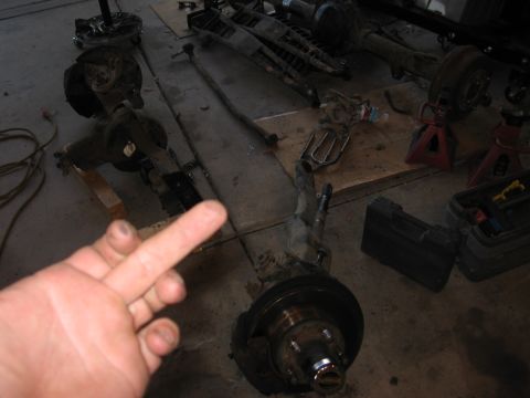 1990 Ford Bronco - Multiple vehicle axle and suspension components are visible on the garage floor.