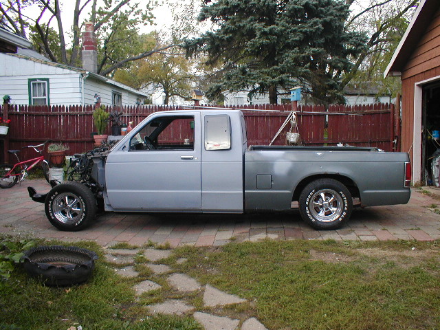 Side view of a light blue and gray pickup truck missing its front end