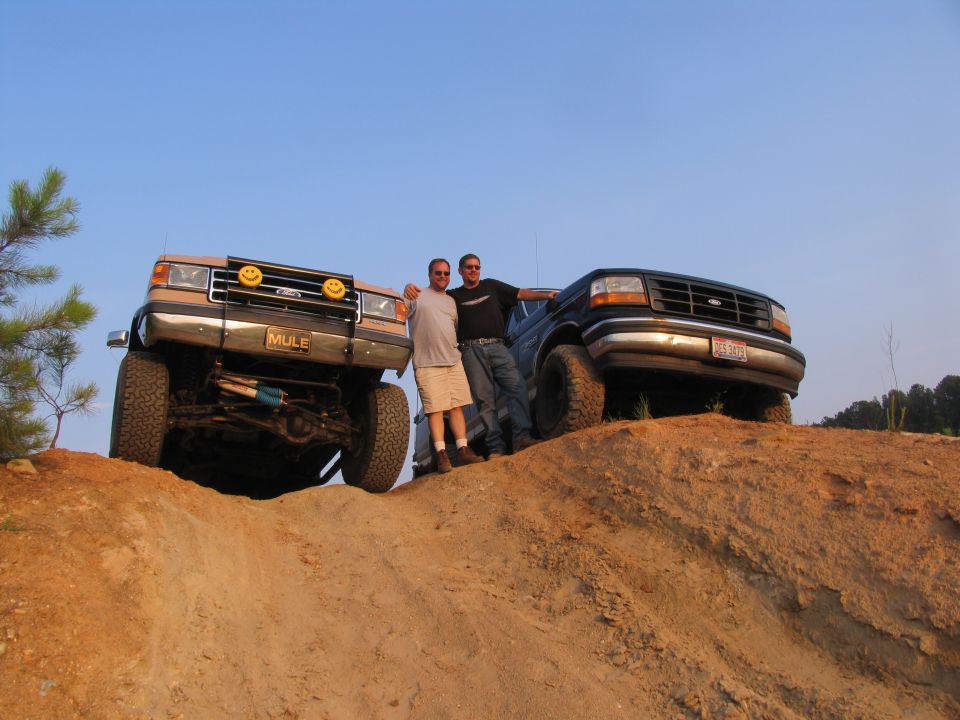 1993 Ford Bronco and another Ford truck on a dirt hill with two men