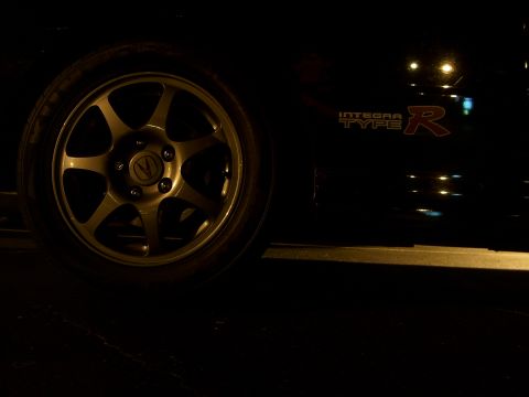 1994 Ford Probe - A close-up shot shows the wheel and side badging of a black vehicle at night.