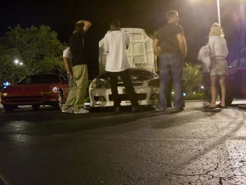 1994 Ford Probe - Several people gather around a white car with its hood open at night, with another red car visible to the left.