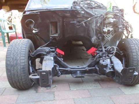 1998 Ford Taurus - The front suspension and chassis of a vehicle are exposed, with the engine bay and wiring visible.