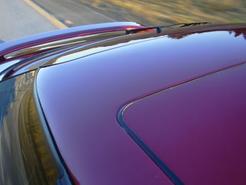 1997 Ford Probe - The roof of a red 1997 Ford Probe is visible, with a sunroof and spoiler, as the car drives down a road.