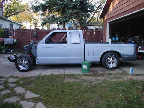 1998 Ford Taurus - A light blue pickup truck is parked in a driveway next to a garage, with its front end disassembled.