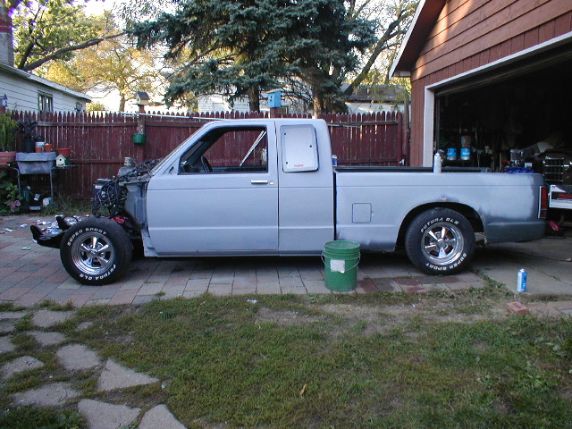 Light blue pickup truck, side view, missing front end, parked in driveway