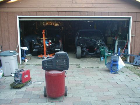 1998 Ford Taurus - Garage scene with two vehicles undergoing work, one being lifted by an engine hoist.